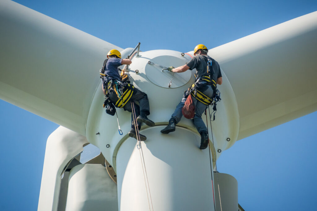 Inspection engineers preparing to rappel down a rotor blade of a wind turbine